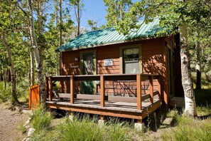 A rustic cabin with a metal roof, a porch with a bench, and a sign warning of roof sheds and snow & ice. - Convict Lake Resort (Mammoth Lakes)