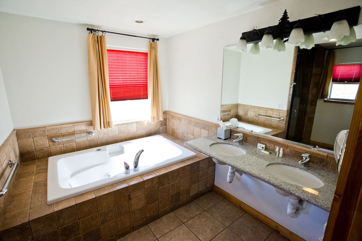 A bathroom with two sinks, a bathtub, and a large mirror.
