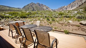 A deck with outdoor furniture, a table, and chairs, overlooking a mountainous landscape. - Convict Lake Resort (Mammoth Lakes)