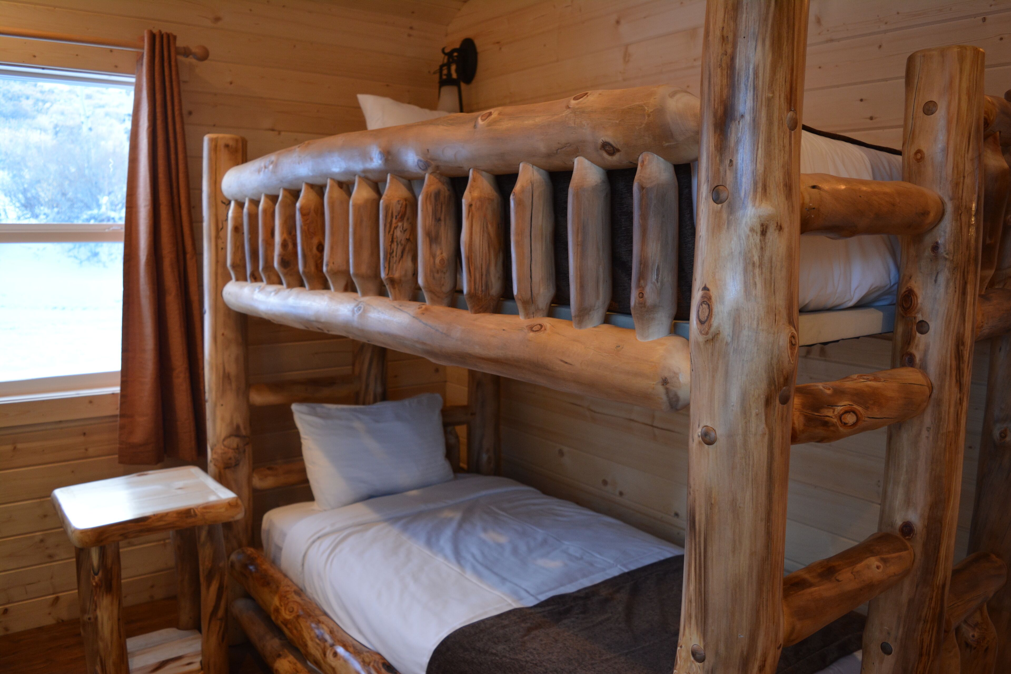 A bunk bed with a wooden frame and a small table beside it.