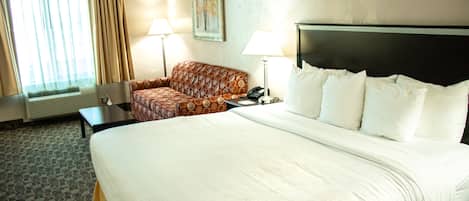 A hotel room with a large bed, a sofa, two lamps, a painting on the wall, and a window with curtains.