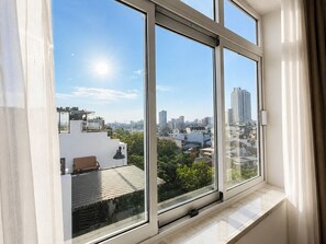 Una ventana con vista a un paisaje urbano, con edificios y áreas verdes.