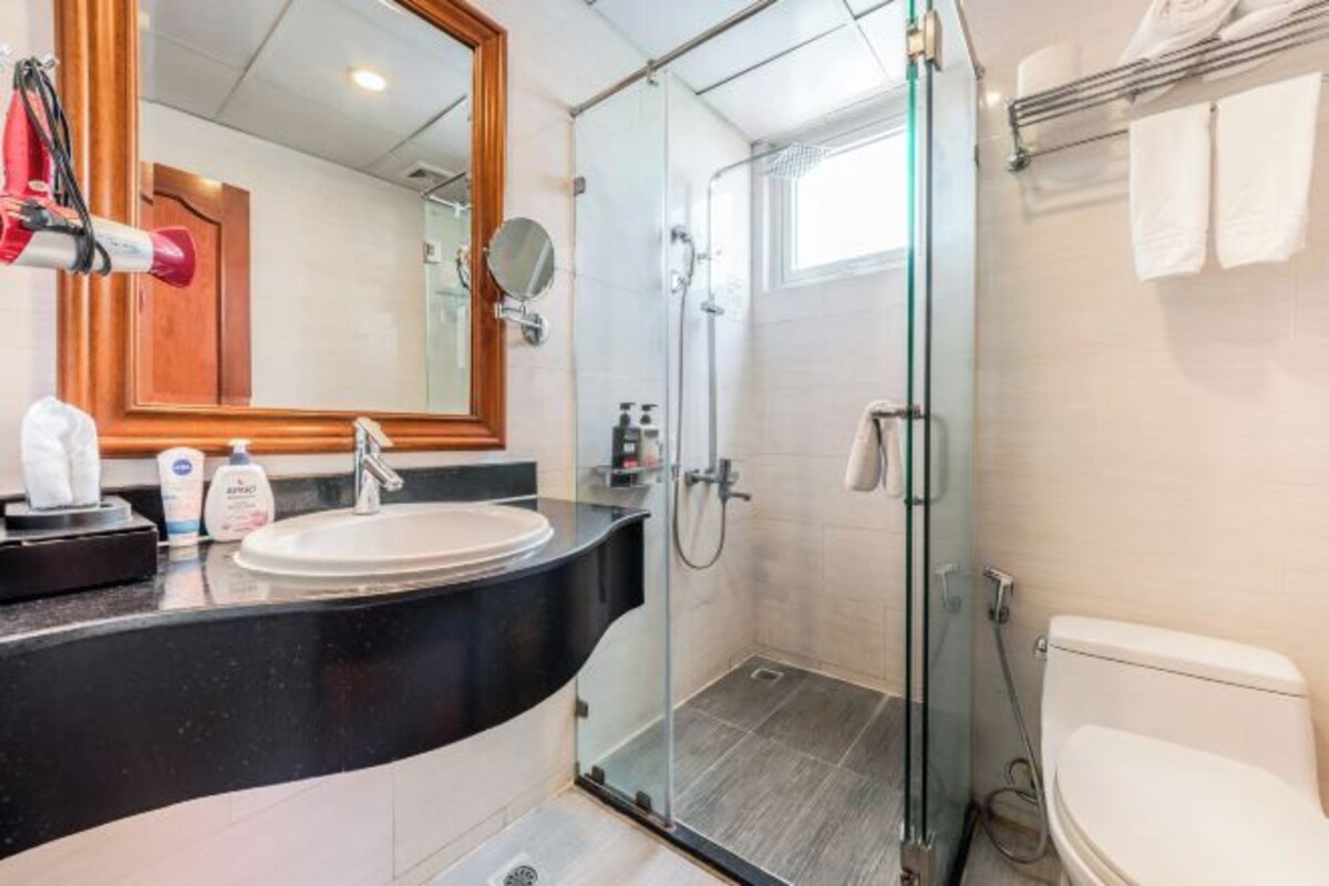 Un baño moderno con ducha envuelta en vidrio, un lavamanos blanco y un espejo grande.