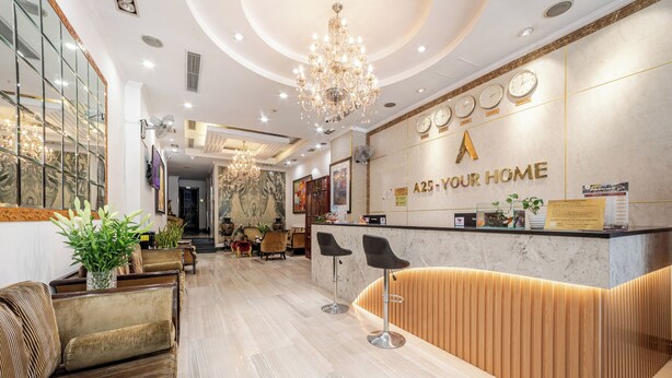 Zona de recepción de un hotel con piso de mármol, mostrador de madera y un candelabro.