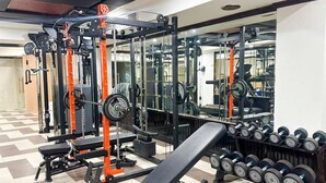 Un gimnasio con equipos de levantamiento de pesas, bancos y mancuernas.