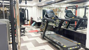 A gym with treadmills, a weight bench, and a mirrored wall.