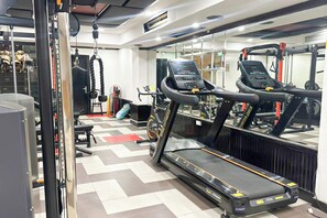 Ein Fitnessraum mit Laufbändern, einer Gewichtbank und einer Spiegelwand.
