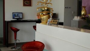 A room with a checkered wall, a red object on a stand, a gold statue, and a framed picture on the wall. - Hotel Star Moon (Malacca City)