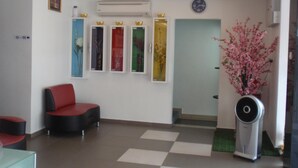 A reception area with a checkered floor, a red and black seating area, a clock, and a wall-mounted air conditioning unit. - Hotel Star Moon (Malacca City)