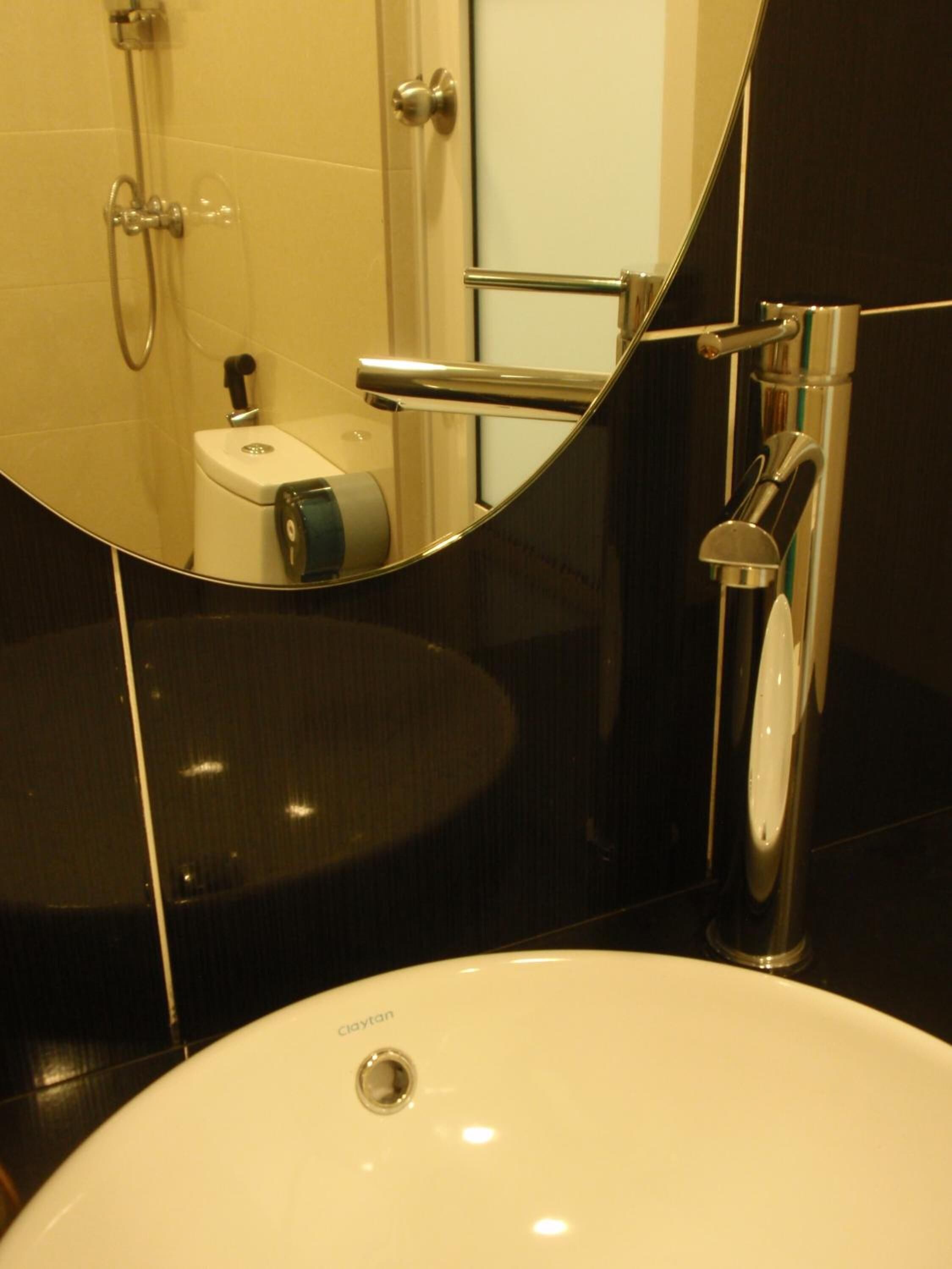 A modern bathroom with a white sink, a mirror, and a shower area.