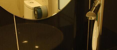 A modern bathroom with a white sink, a mirror, and a shower area.