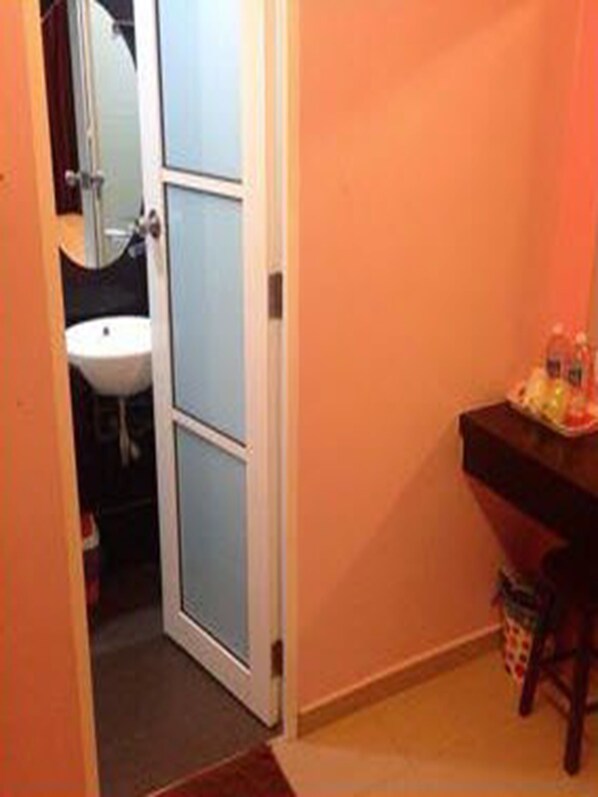 A bathroom with a sink, mirror, and a small stool with toiletries.