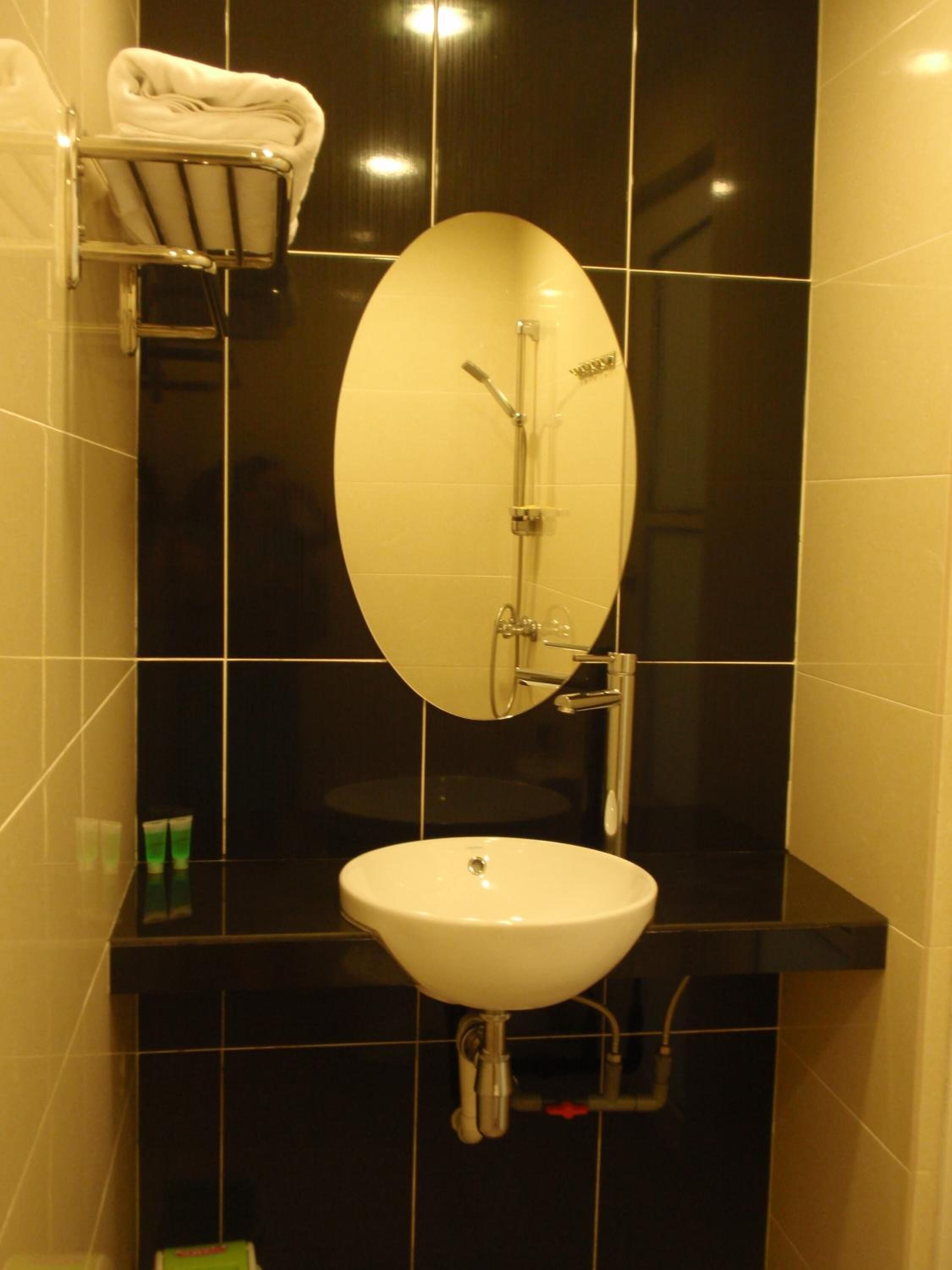 A bathroom with a white sink, a mirror, and a towel rack.