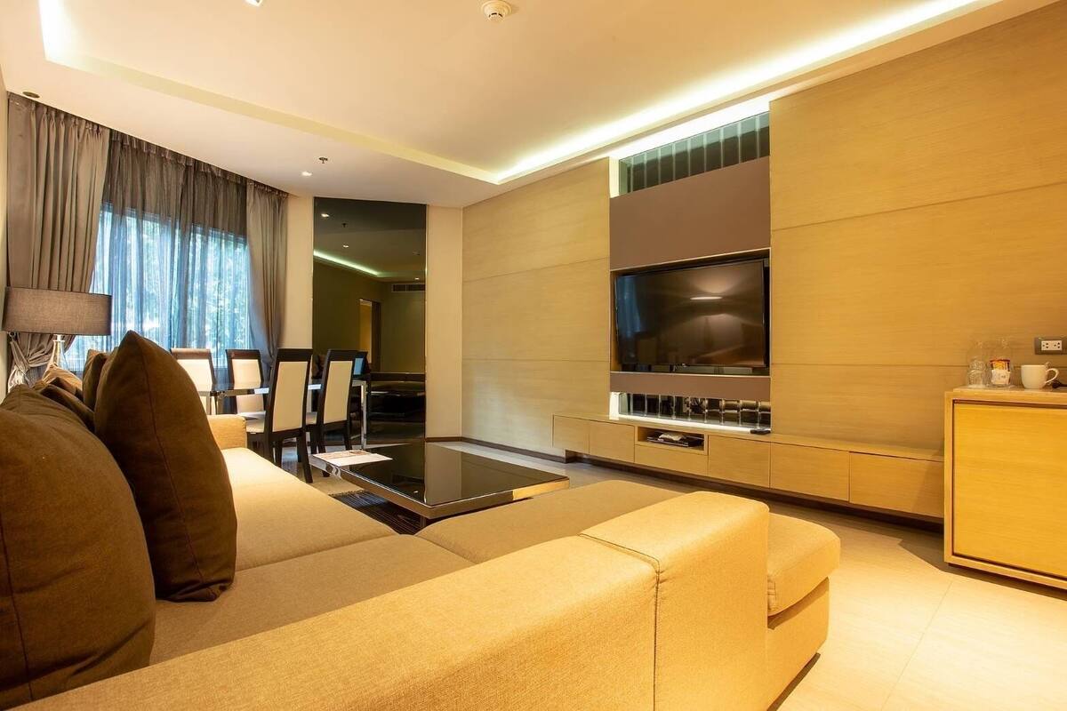 Un salon moderne avec un canapé, un téléviseur à écran plat et une table basse en verre.