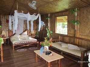 A traditional room with a bed, a sofa, a table, and a window. - Coco Beach Island Resort (Puerto Galera)