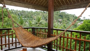 A hammock hanging on a wooden deck with a view of a lush, green landscape. - Coco Beach Island Resort (Puerto Galera)