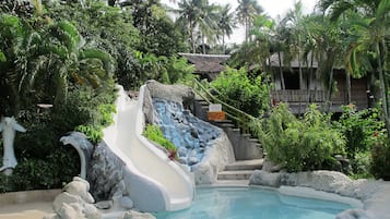 Relax by the pool surrounded by lush greenery and natural rock formations.