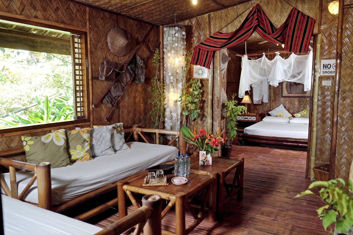 A traditional bamboo room with a bed, a sofa, and a dining area.