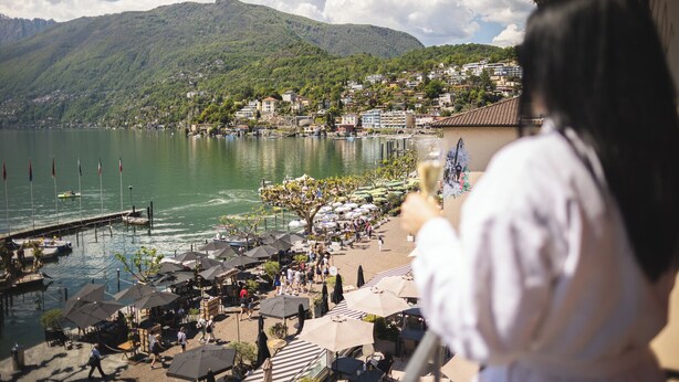 A lakeside town with outdoor seating and a view of mountains.