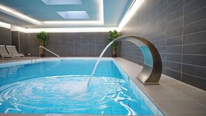 An indoor swimming pool with clear water, a modern design, and a skylight above.