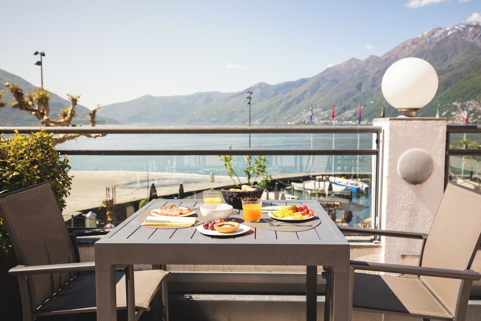Una mesa con alimentos para el desayuno, vista al mar y montañas al fondo.