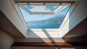 A skylight with a view of a lake and mountains.
