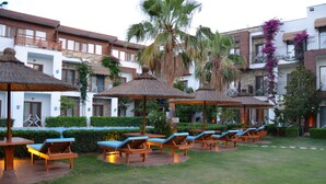 A courtyard with lounge chairs and umbrellas, surrounded by buildings with balconies and greenery. - Liona Hotel (Bodrum)