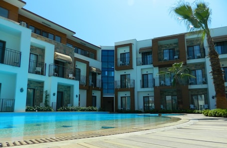 Una piscina al aire libre, sombrillas, sillones reclinables de piscina