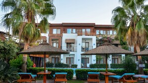 A hotel with a pool area, outdoor seating, and palm trees. - Liona Hotel (Bodrum)