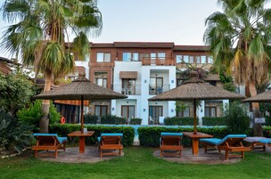 Un hotel con piscina, zona de estar al aire libre y palmeras.