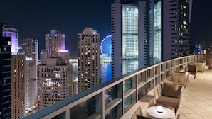 A rooftop terrace with outdoor seating and a view of a city skyline at night. - InterContinental Dubai Marina by IHG (Dubai)