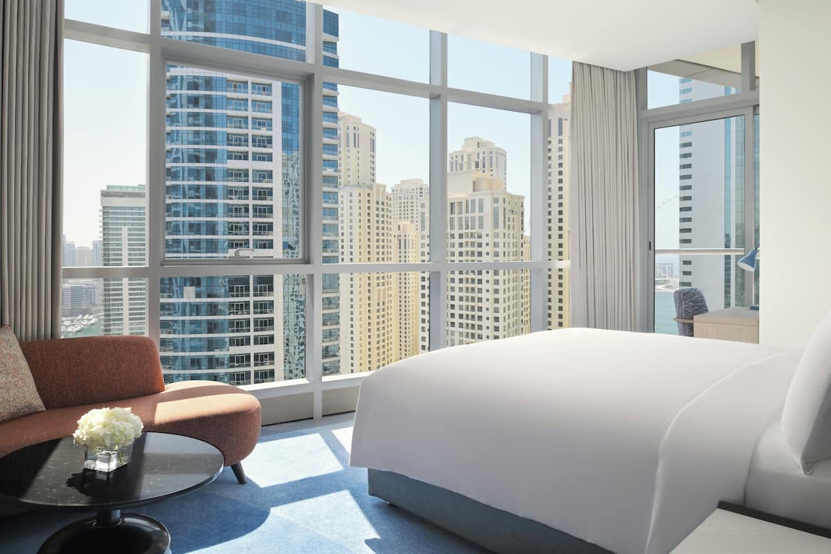 A hotel room with a large window, a bed, a sofa, and a coffee table.