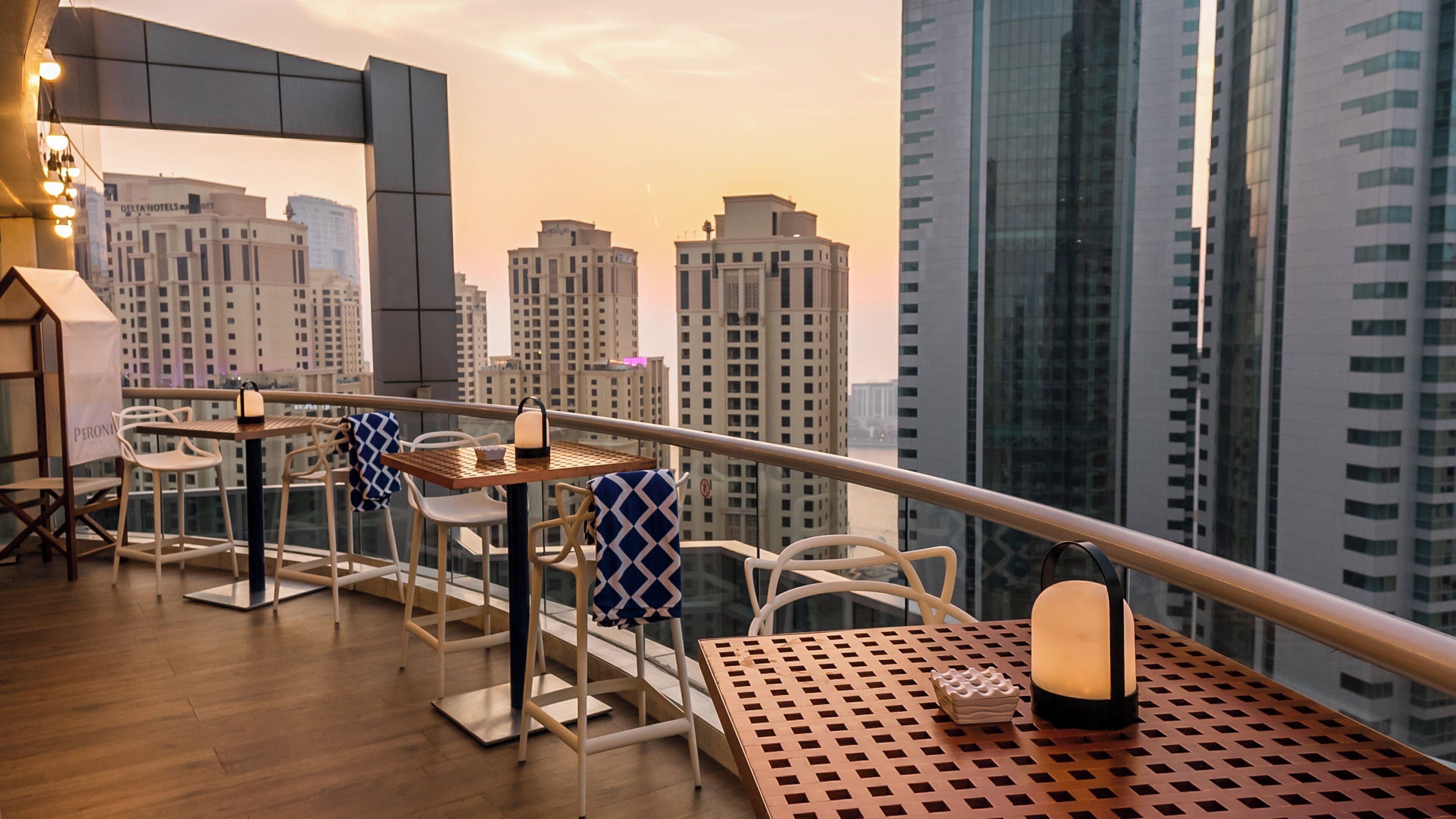 Une terrasse sur le toit, aménagée avec des tables et des chaises, d’où l’on peut admirer une vue panoramique sur la ville, avec ses nombreux immeubles de grande hauteur.