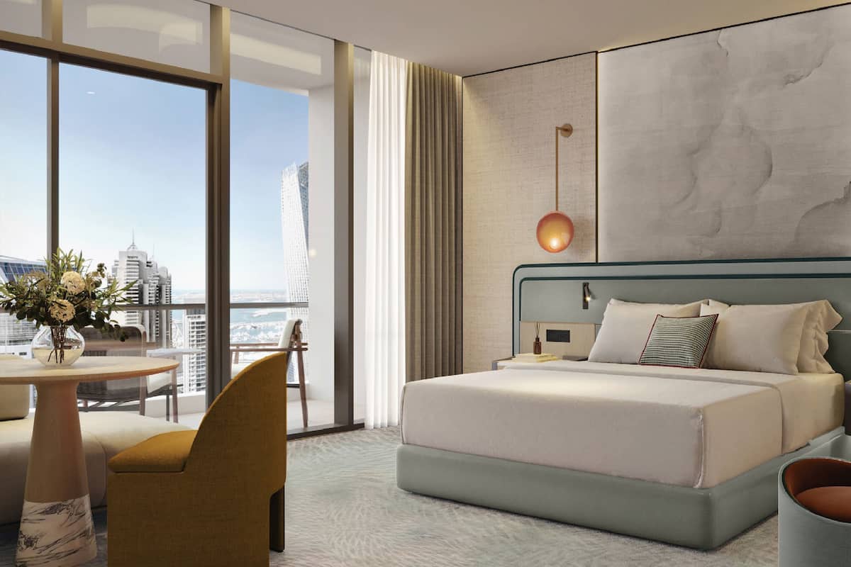 A modern hotel room with a large bed, a desk, and a chair.