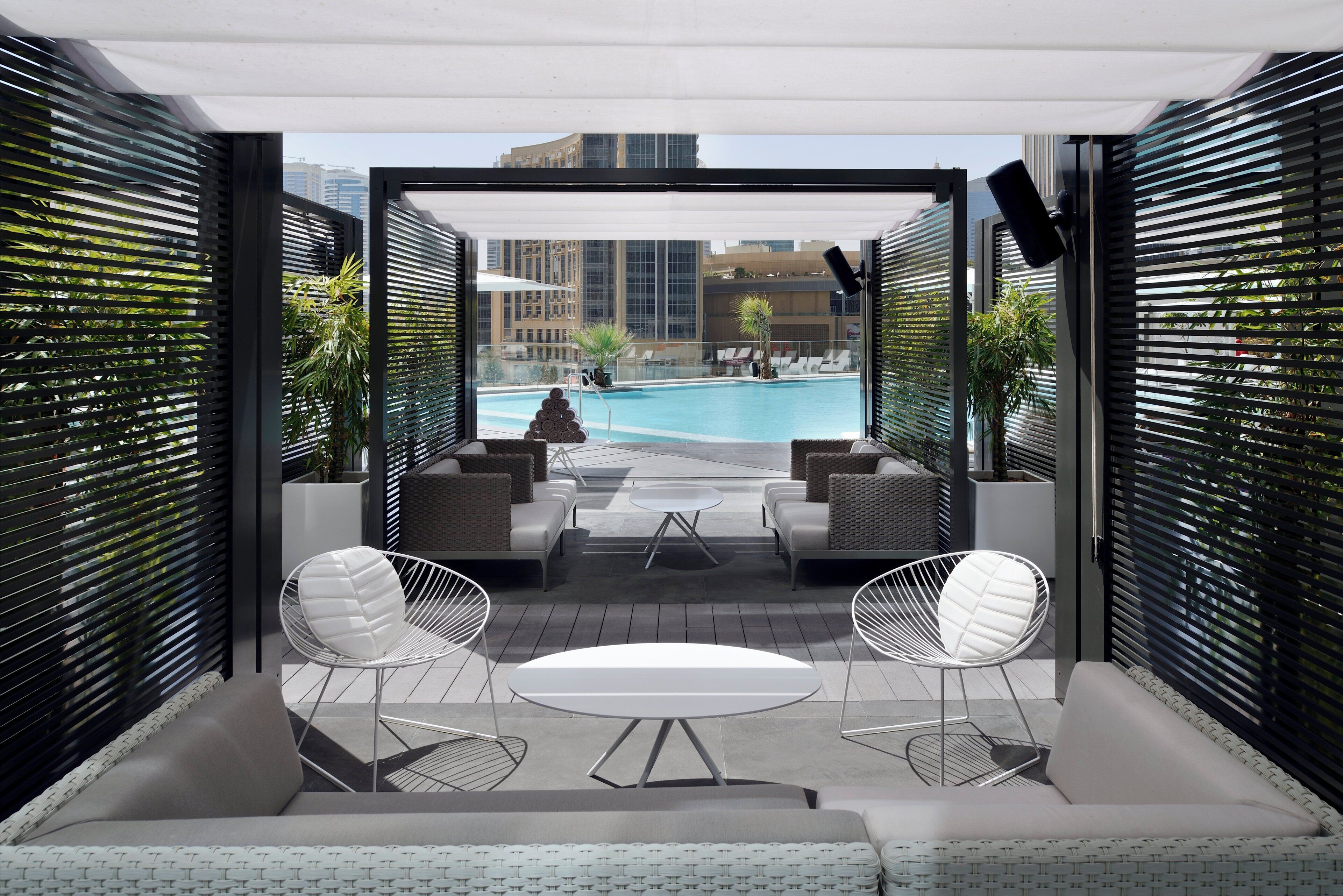 Ein Außenbereich mit Sitzgelegenheiten und Blick auf den Pool, ausgestattet mit modernen Möbeln und freiem Ausblick.
