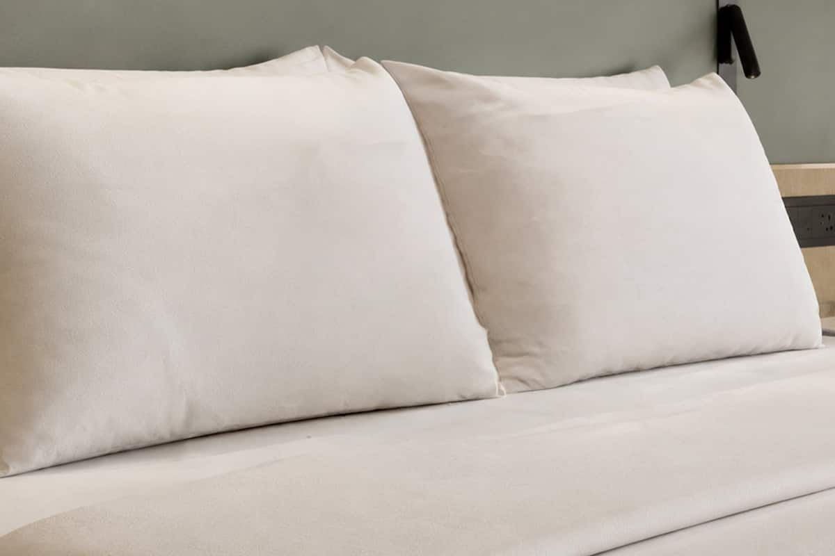 A bed with two pillows and a wooden headboard.