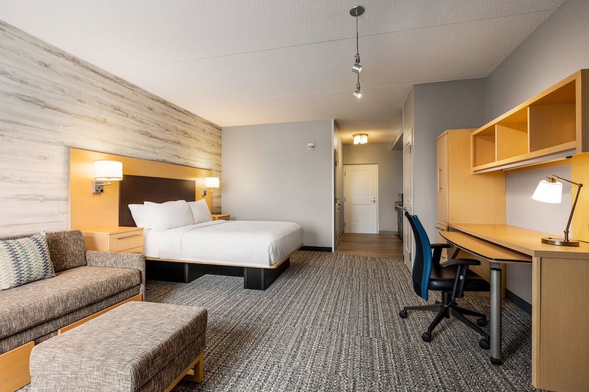 Una habitación de hotel con cama, escritorio, silla, sofá y una mesita.