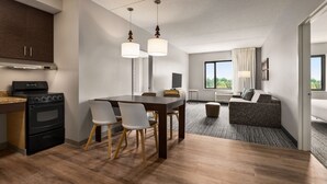 Une cuisine moderne équipée d’une cuisinière, d’un four et d’un coin repas avec des chaises et une table.