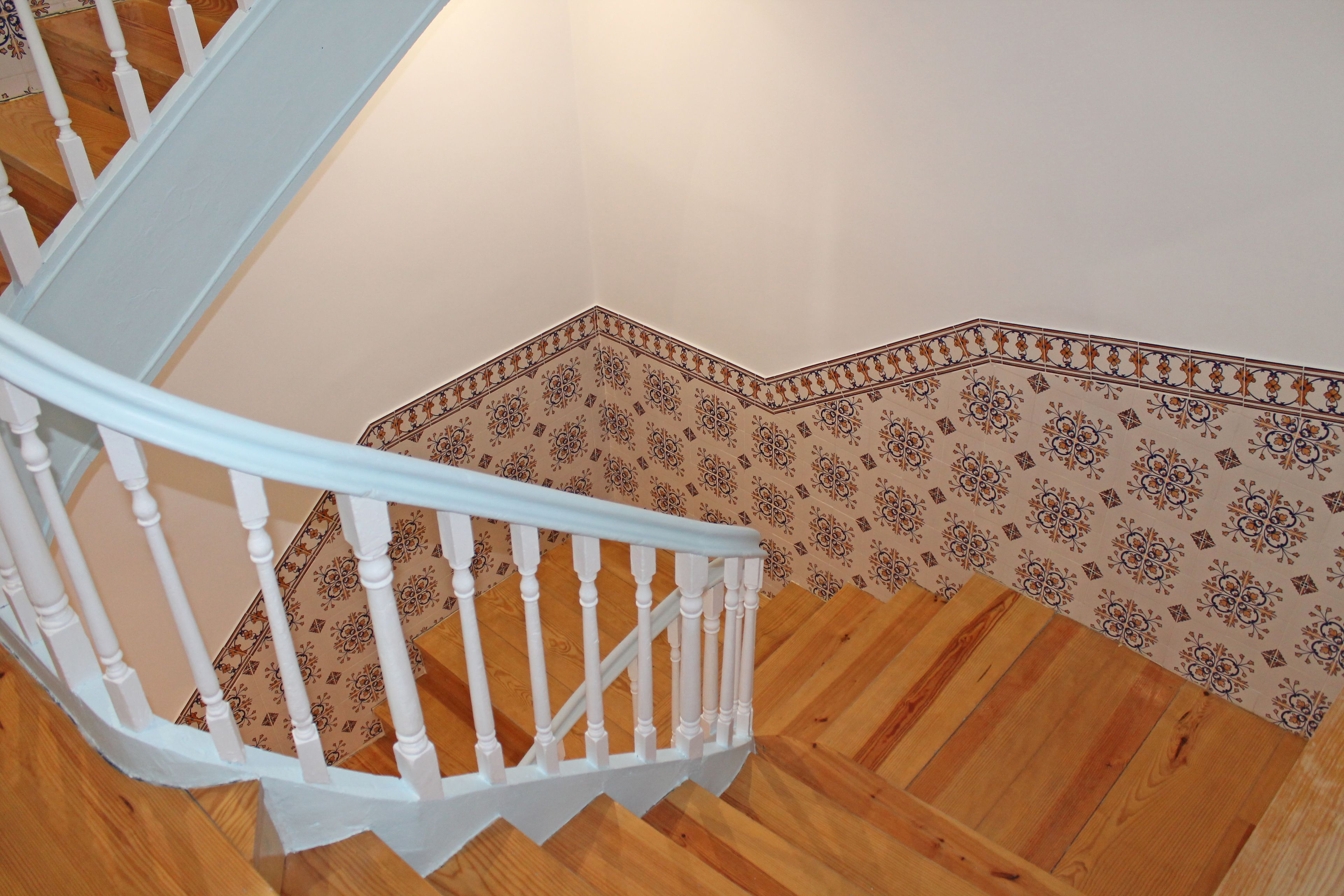A staircase with white balusters and patterned wall tiles.