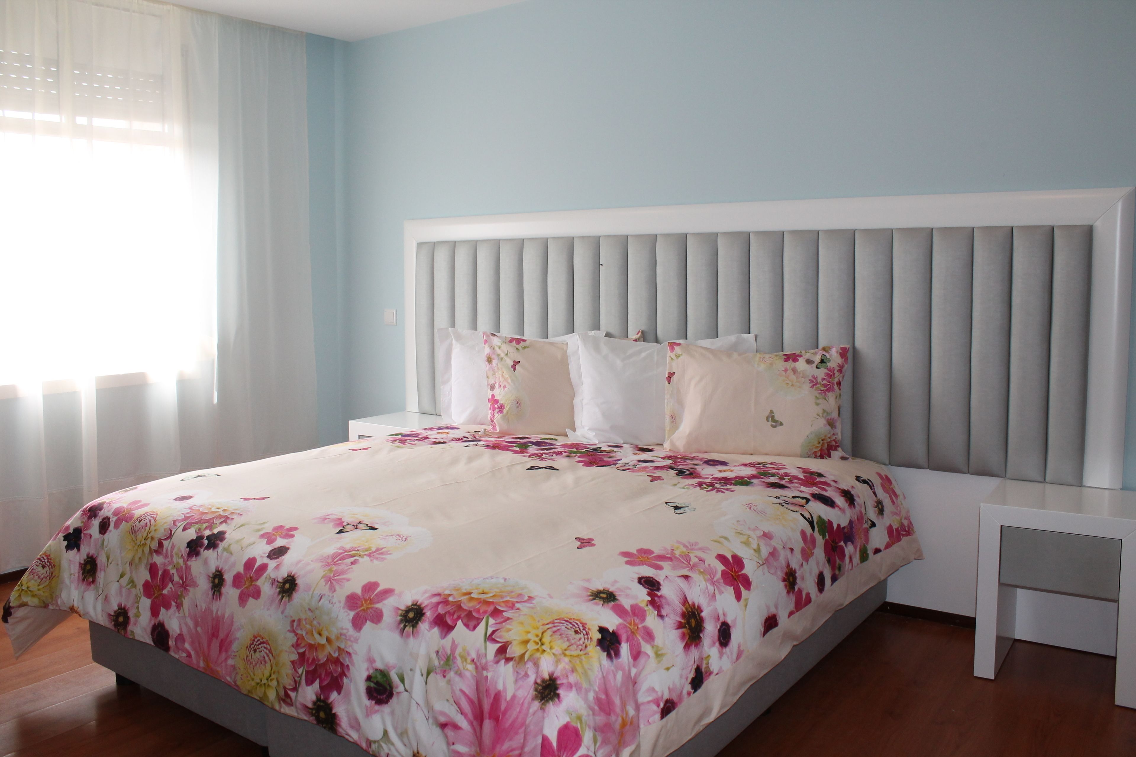 A bedroom with a bed, a nightstand, and a window with curtains.
