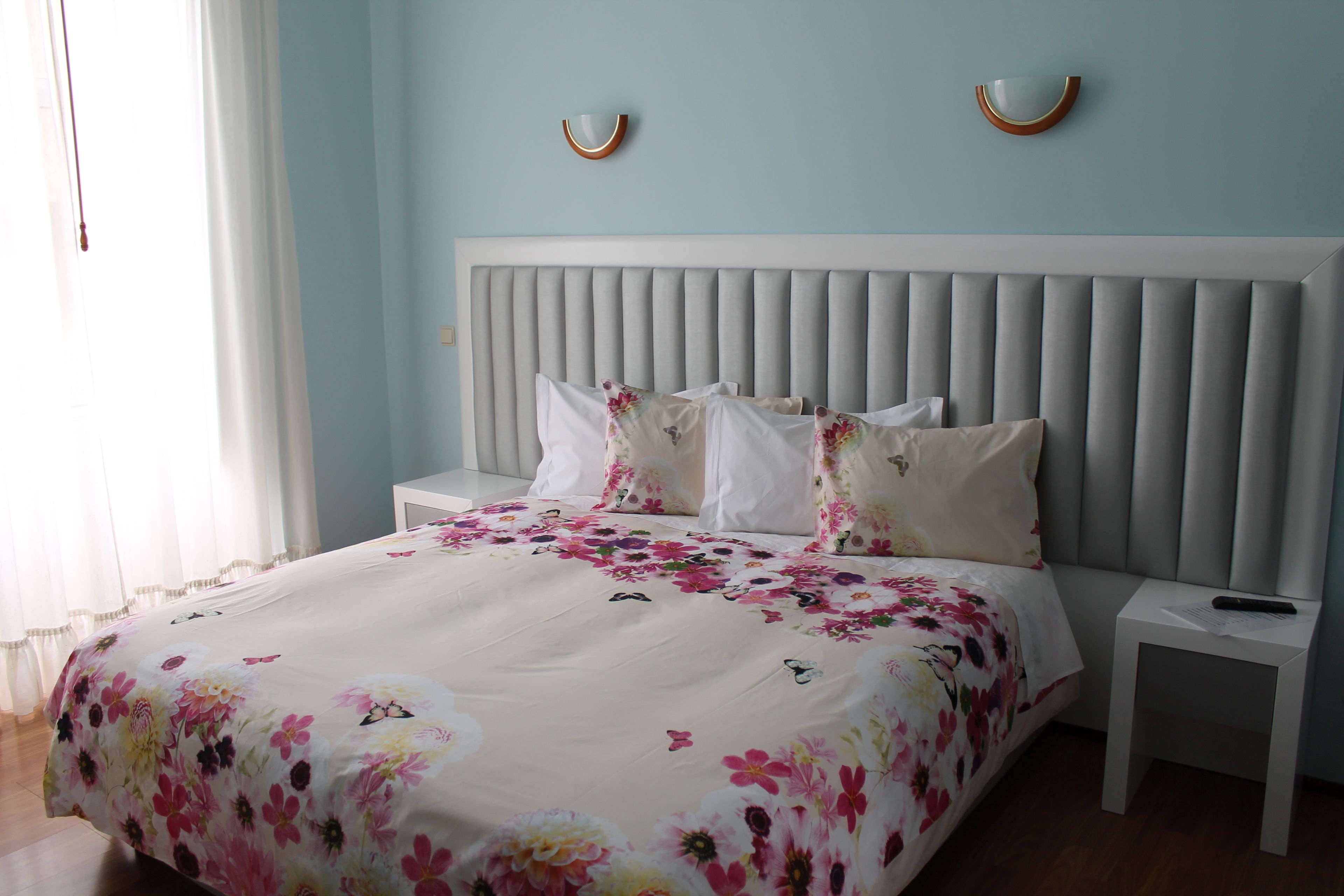 A bedroom with a bed, nightstands, and a headboard.