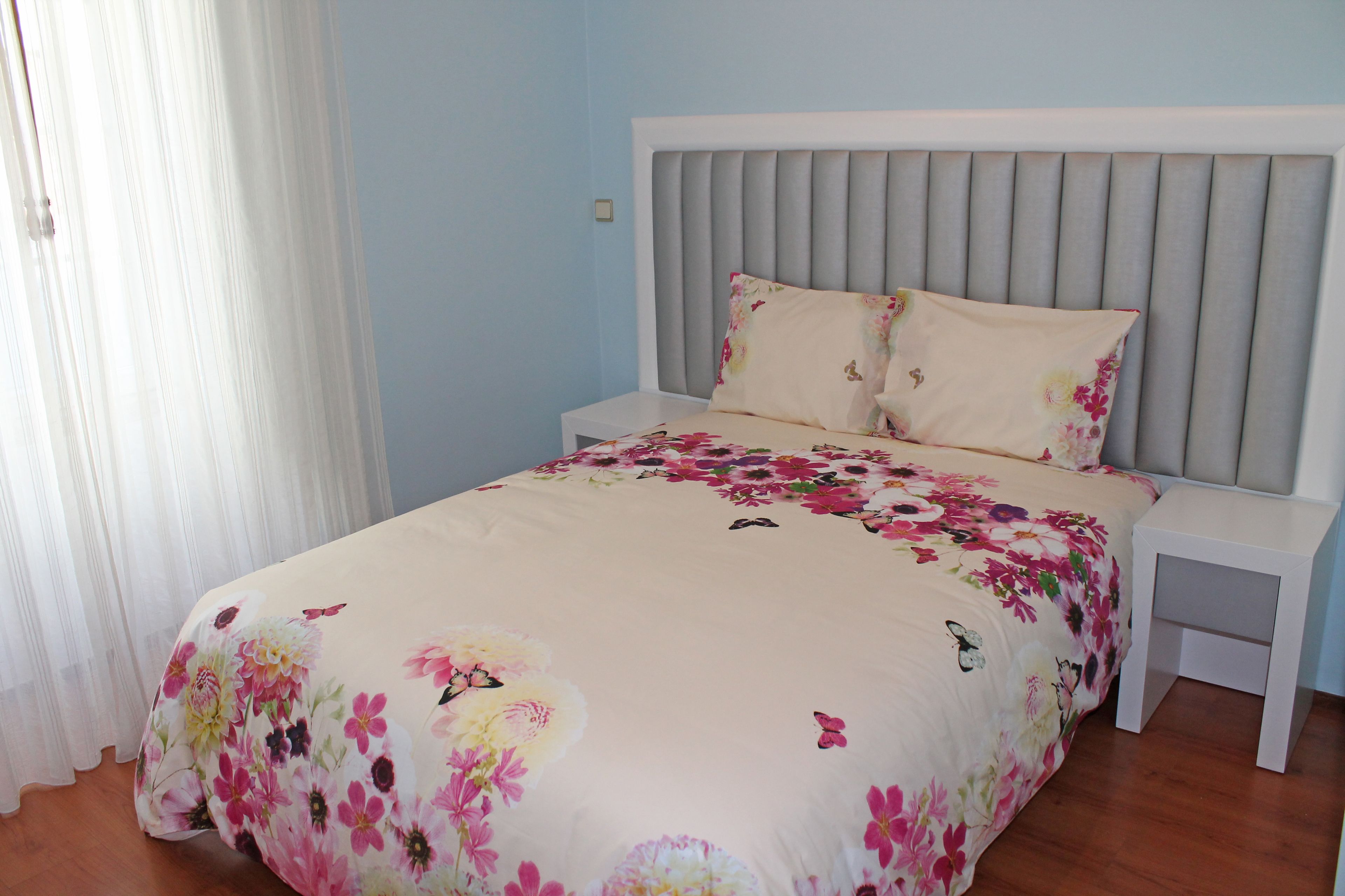 A bedroom with a bed, nightstands, and a window with curtains.
