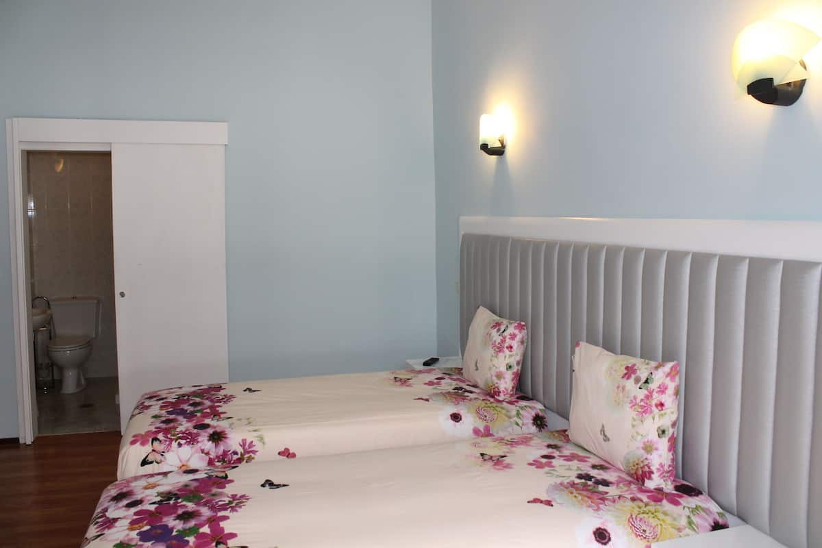Een slaapkamer met een bed, een hoofdeinde en een wandlamp.