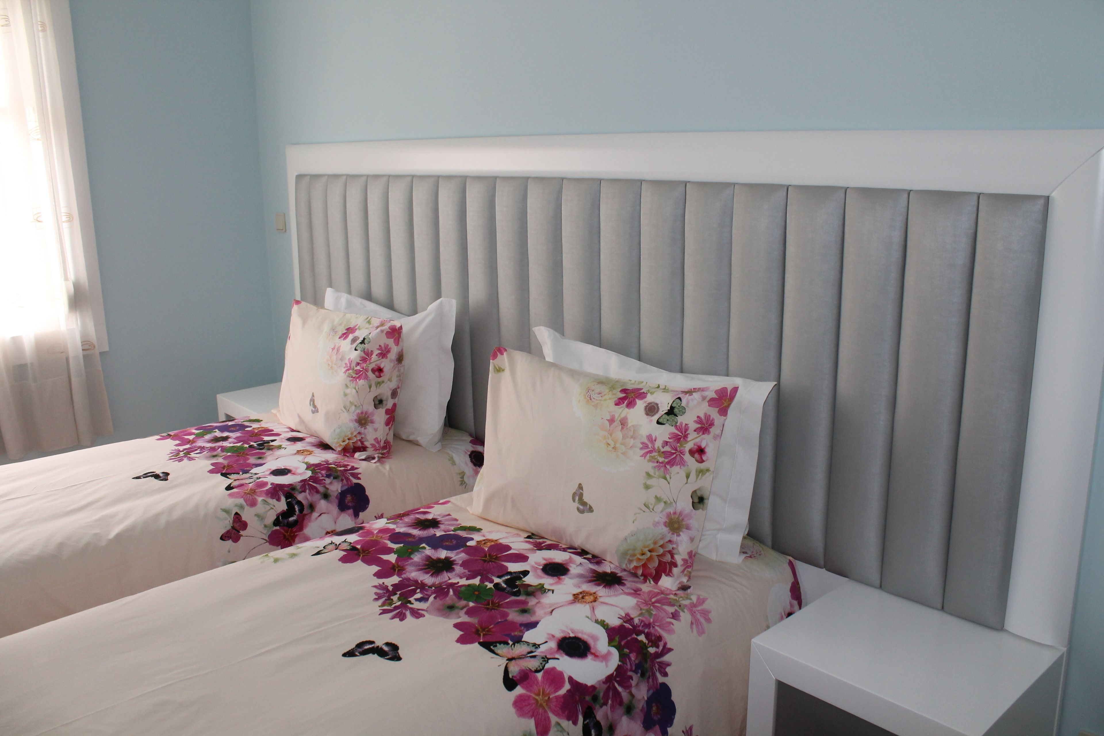 A bedroom with two beds, each with floral bedding and matching pillows.