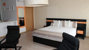 Un dormitorio con una cama, dos sillas, un espejo y un armario de madera.