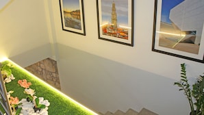 A staircase with a green artificial grass border, framed pictures of a cityscape and a building, and a potted plant. - VivaCity Porto (Porto)