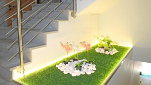 A staircase with a metal railing and a planter with white pebbles and pink and white flowers on a green artificial grass surface. - VivaCity Porto (Porto)