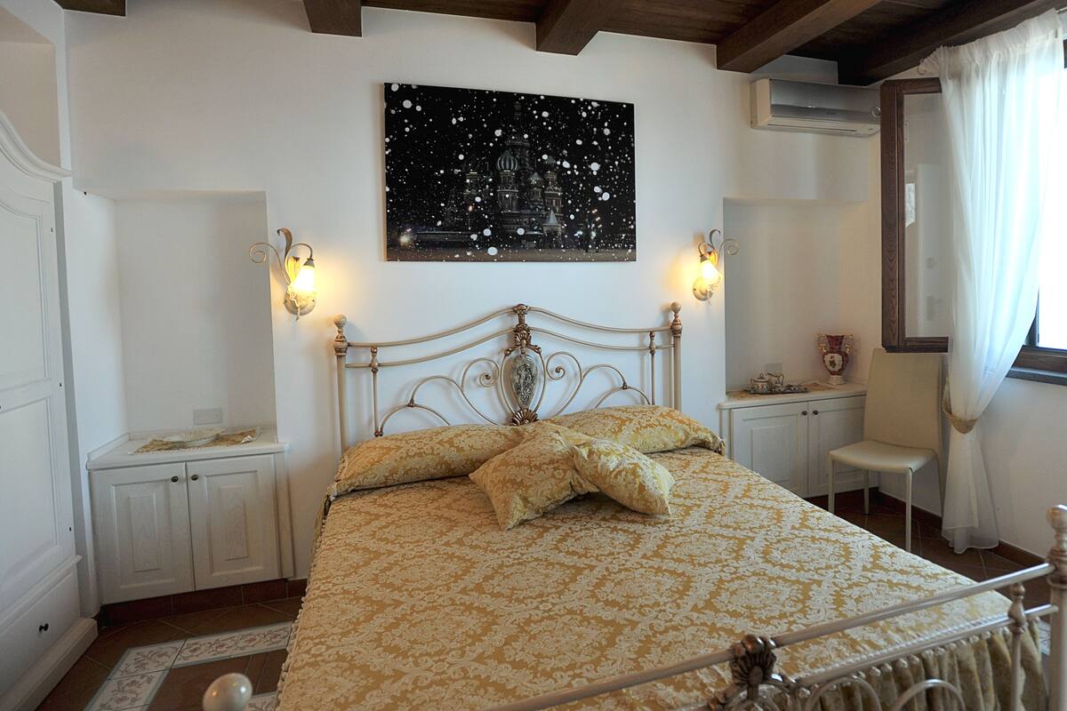 Un dormitorio con cama, dos lámparas de pared, una obra de arte con cielo estrellado y una ventana con cortinas.