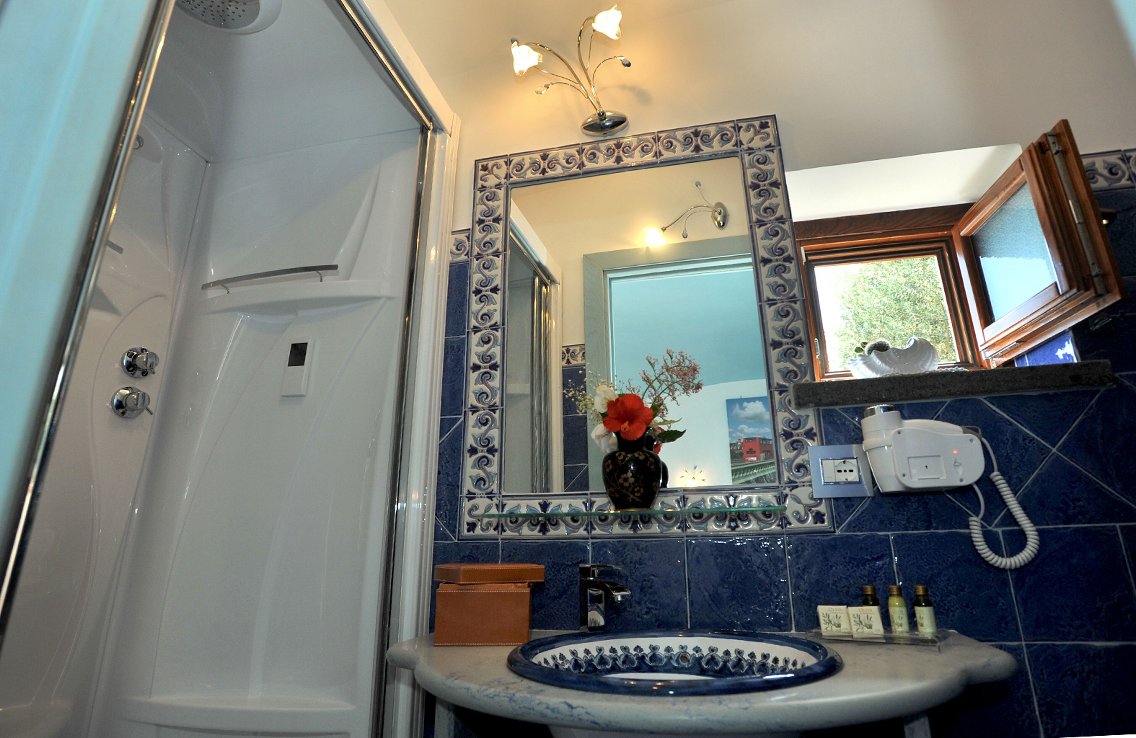 Un baño con bañera, un lavabo con un florero y un espejo con marco decorativo.