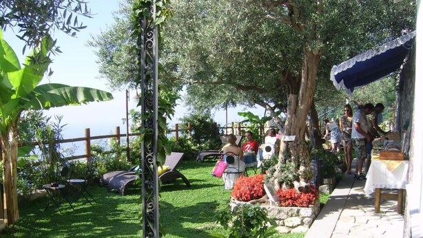 Um jardim com caminho de pedra, área de estar ao ar livre e vista para o mar.
